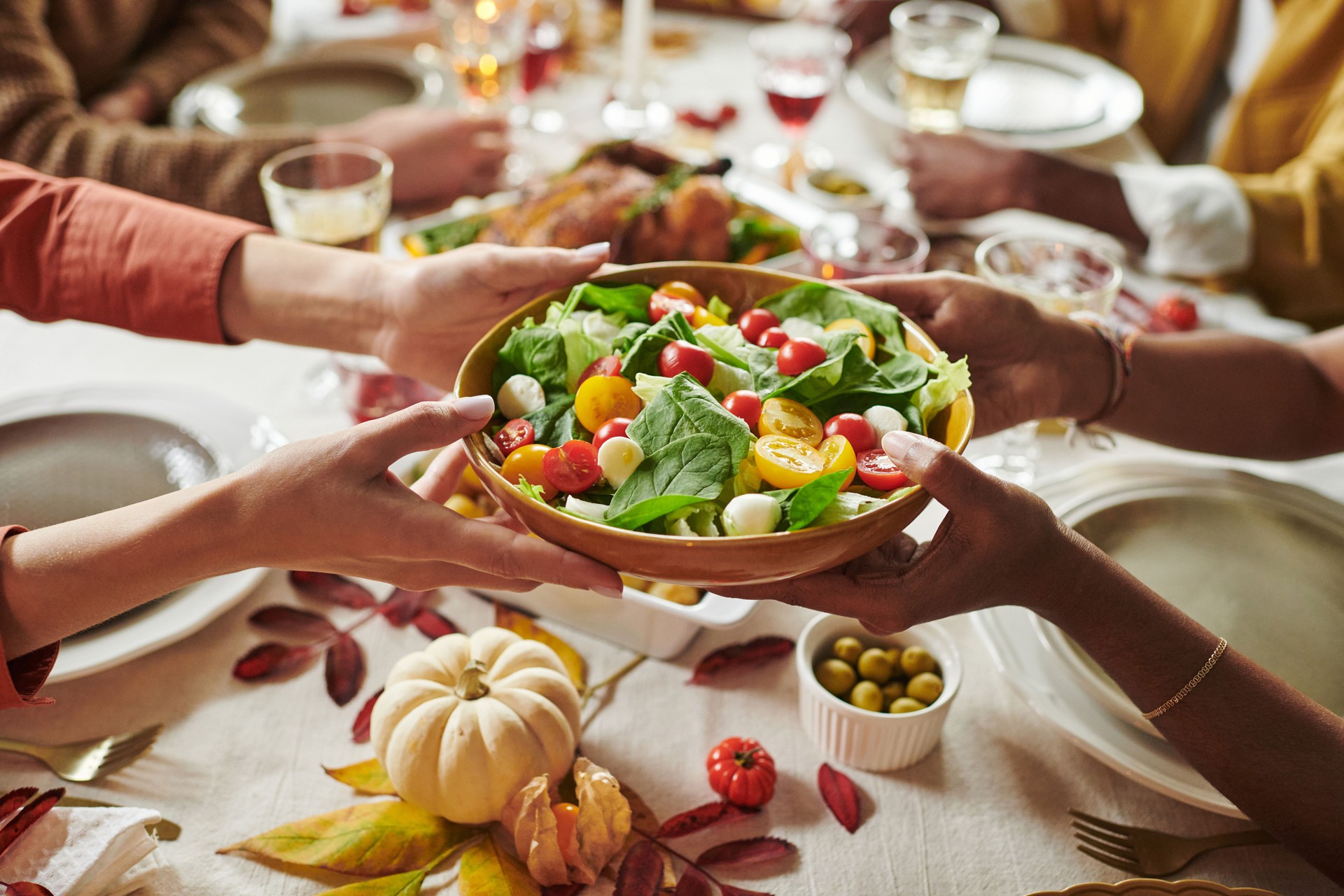 Multiethnic Adults Sharing Fresh Salad during Thanksgiving Holiday Meal Gathering
