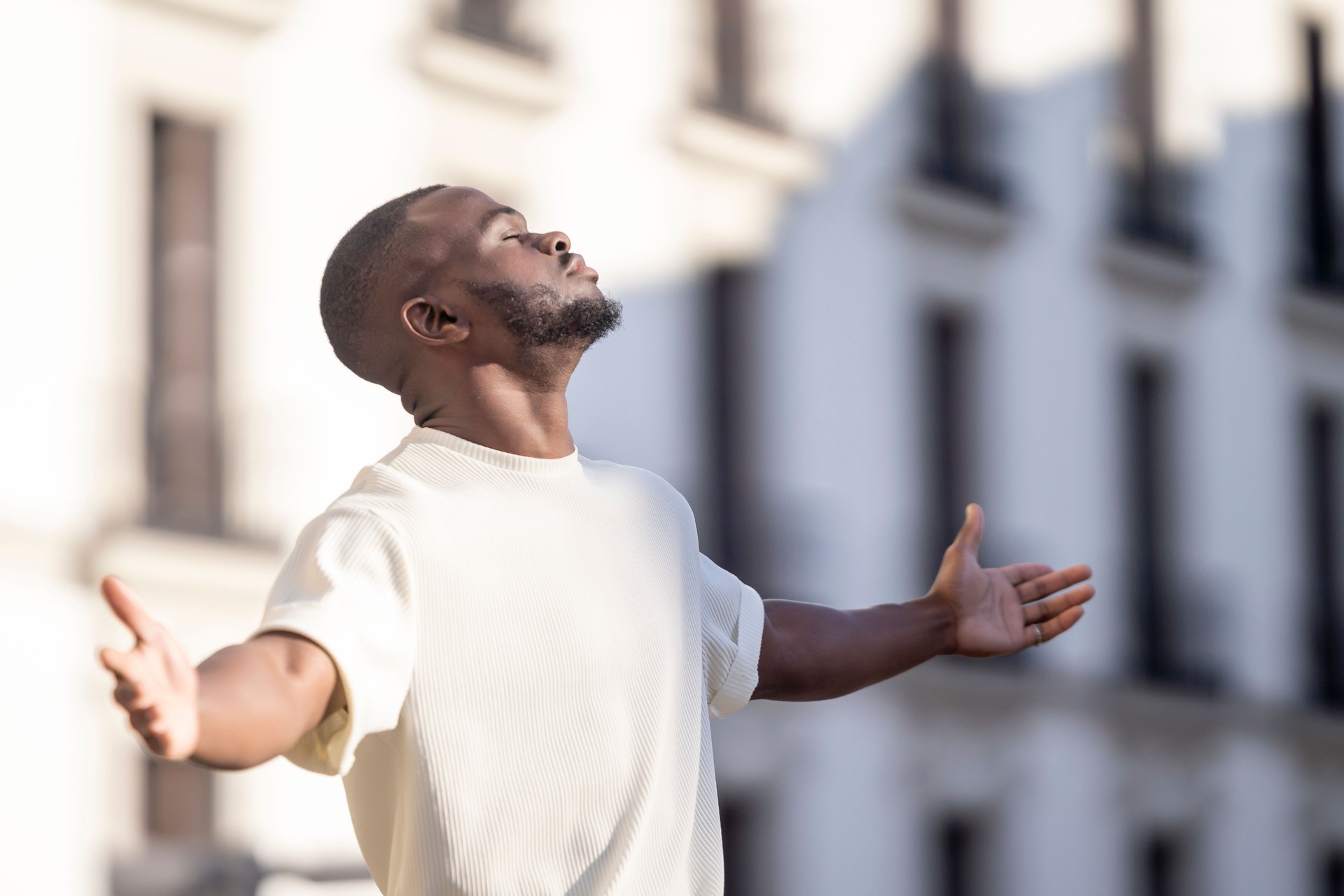 Closed eyes man with black skin relaxed breathing fresh air in the street